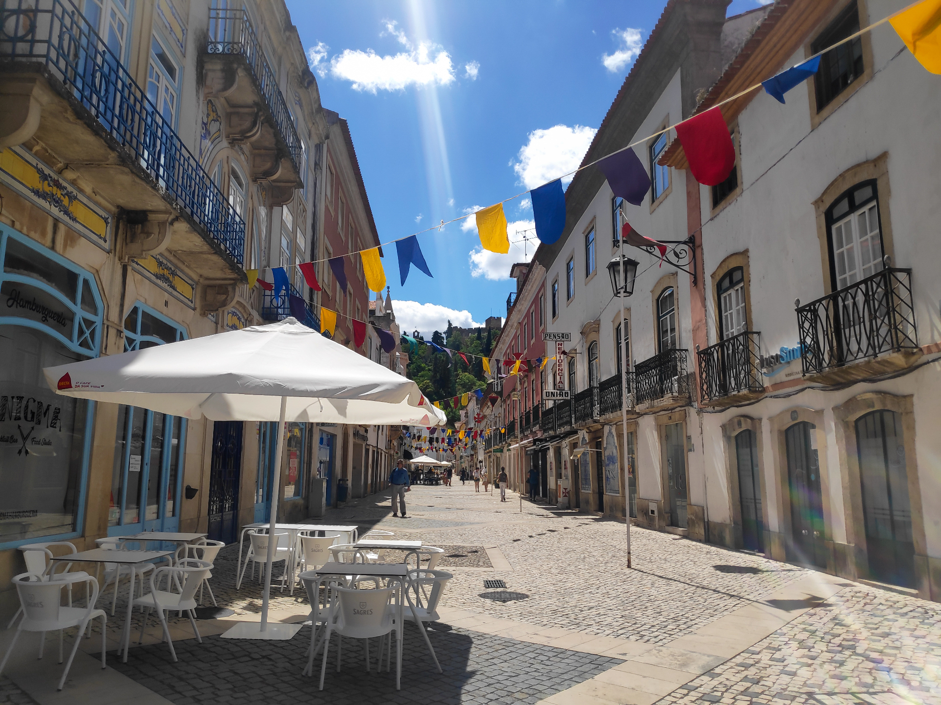 Rua Serpa Pinto in Tomar, with bunting overhead and the hill of the Convent of Christ beyond